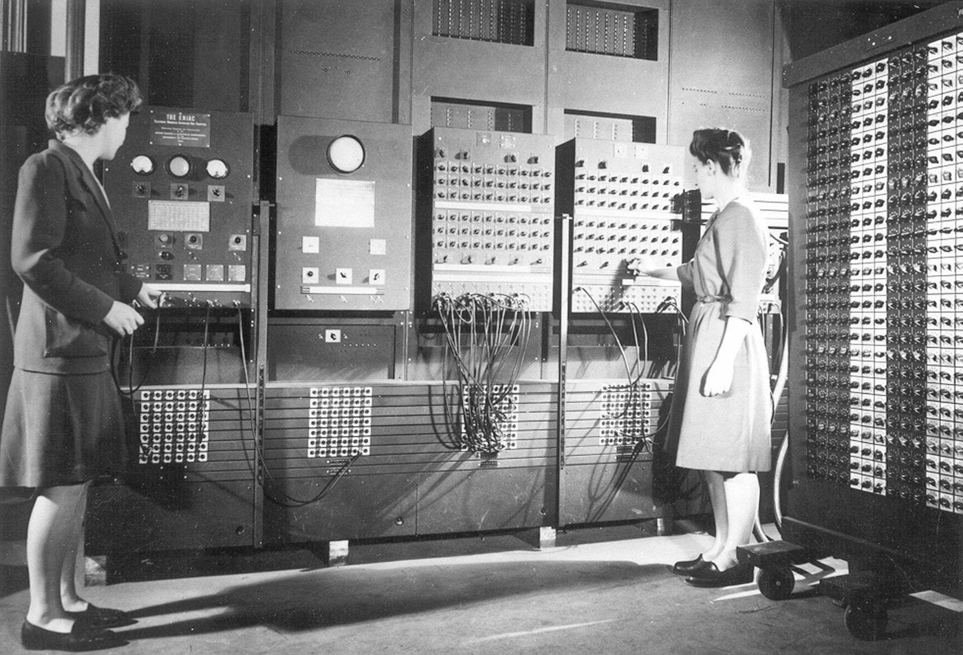 ENIAC filling a room, its vacuum-tube racks and patch cabling covering every wall.