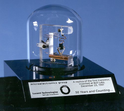 A replica of the first point-contact transistor under a glass dome.